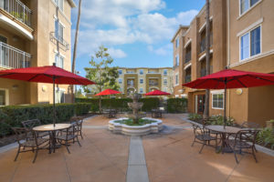 outdoor space with tables and chairs and a fountain in the center