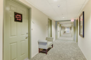 carpeted hallway with green doors