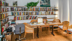 St. Johns Manor Library Room, multiple shelves of books, long table for reading and puzzles. wood floors, white walls.