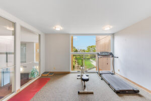 Interior Fitness Room, Treadmill, Stationary bicycle, large window with view of St. Johns Manor Courtyard, padded floor, yoga matt.