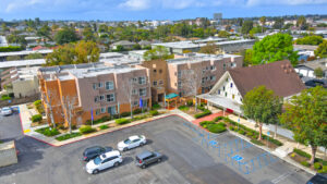 Aerial Exterior of St. Johns manor building and parking lot, three story, meticulous landscaping leading to the building entrance.