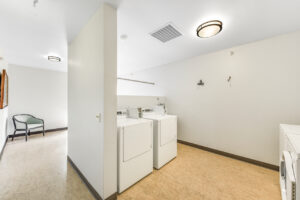 Interior Laundry facilities, 2 washers, 2 dryers, white walls, tile flooring.