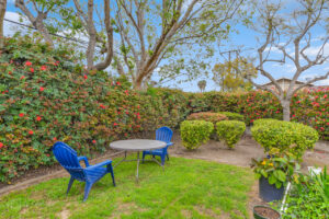 Exterior courtyard, 4 seat tables arranged around the courtyard, meticulous landscaping, high bushes meaning privacy from the street.