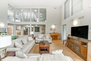 Interior Clubhouse/ leasing office lobby, 2 large couches, contemporary design, white walls, wood floors, 2 lounge chairs, multiple floral paintings