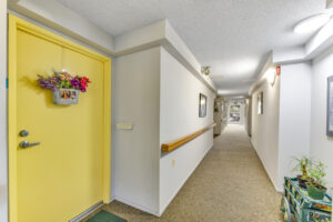 Interior Hallway, white walls, textured carpeting, wall art throughout the hallway.